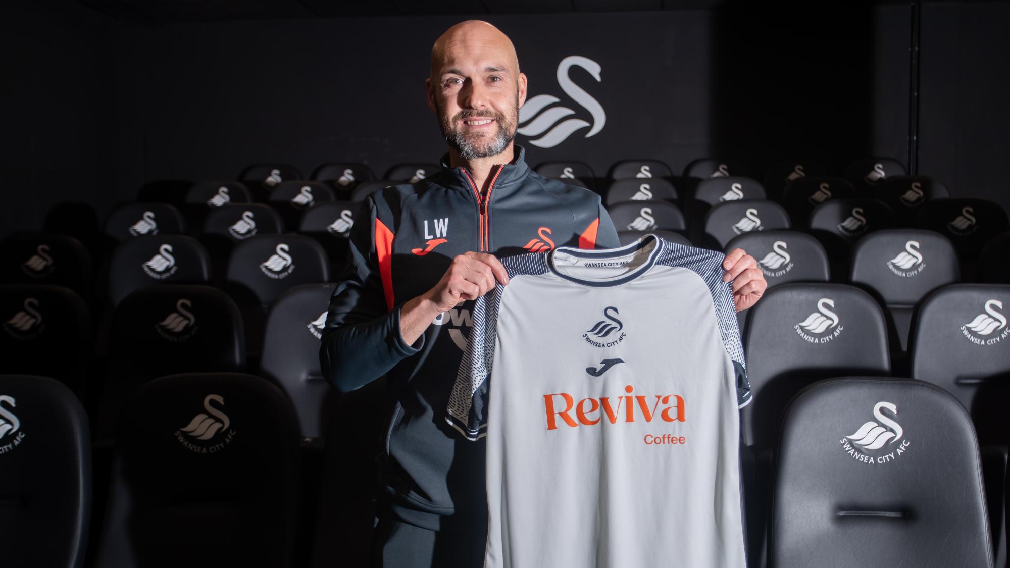 Luke Williams holding up a Swansea City shirt